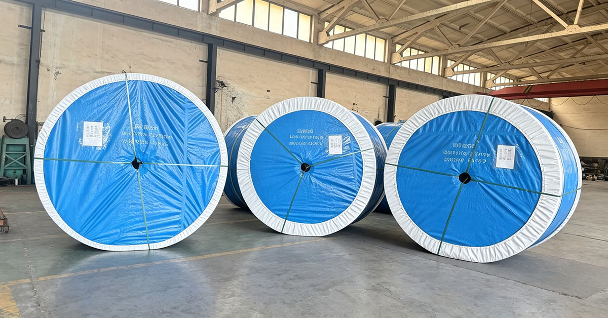 Rubber conveyor belt rolls with blue export packaging stored in factory warehouse
